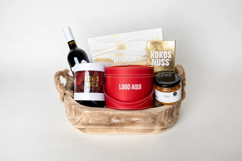 Canasta de madera con vino, tambor rojo con logo y repostería