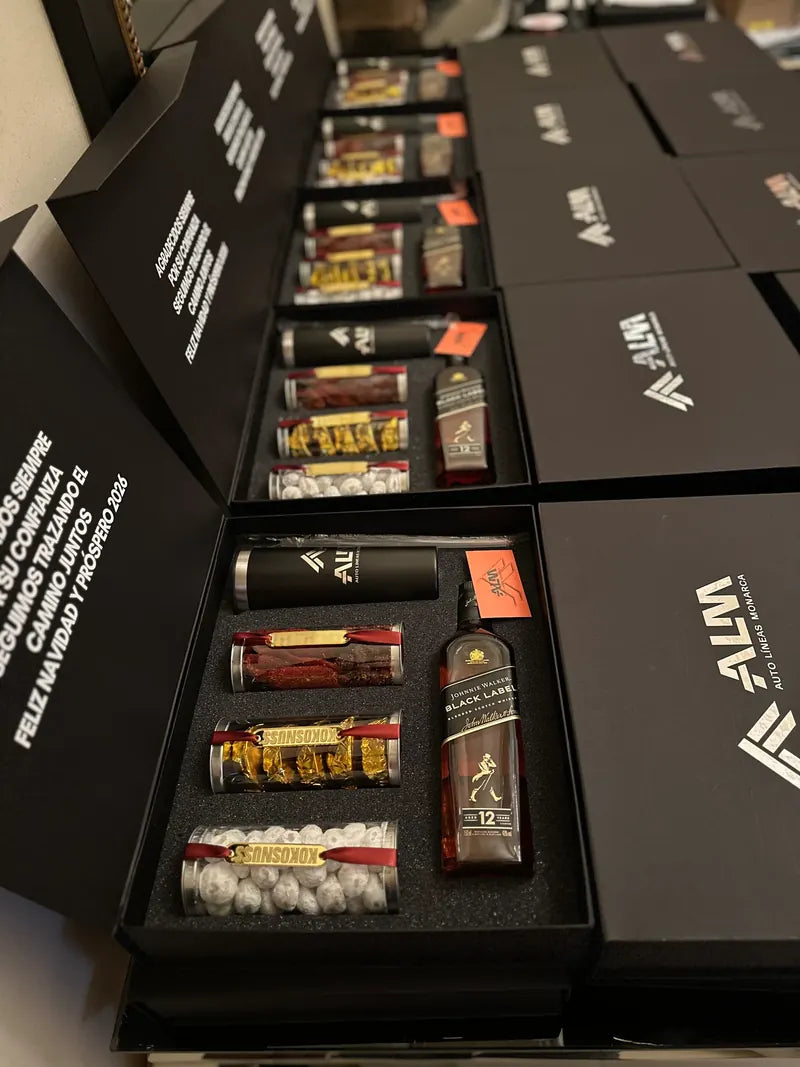 Cajas negras con tequila, repostería y logo ALM