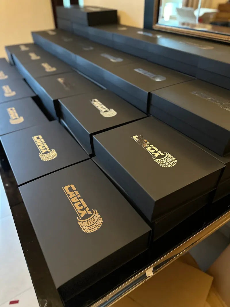 Cajas largas negras con logo Cavox en dorado